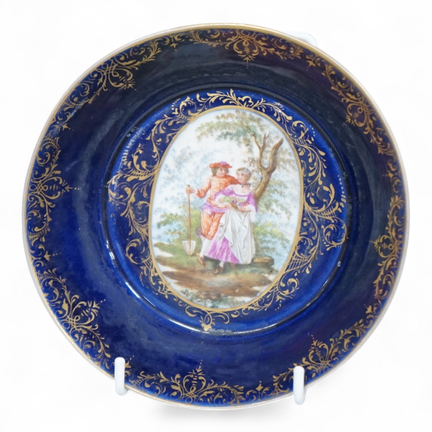A 19th century Vienna saucer, hand painted with two figures beneath a tree, 15cm in diameter